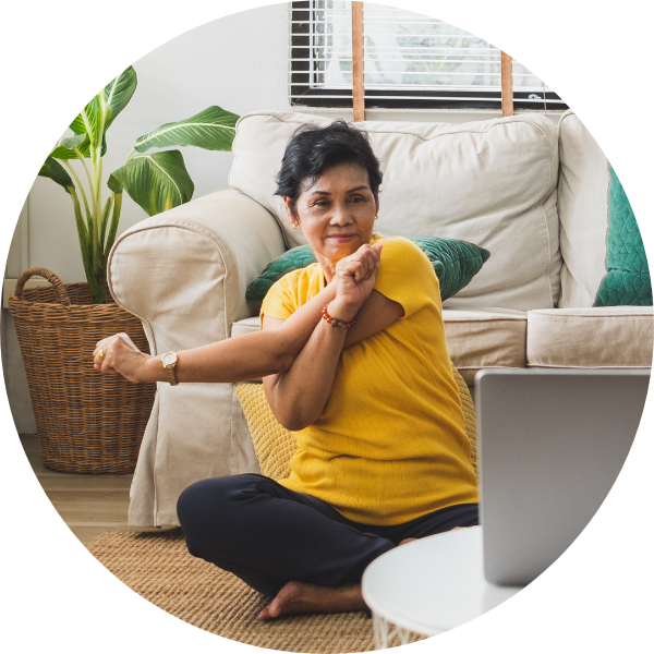 Senior woman stretching while watching laptop