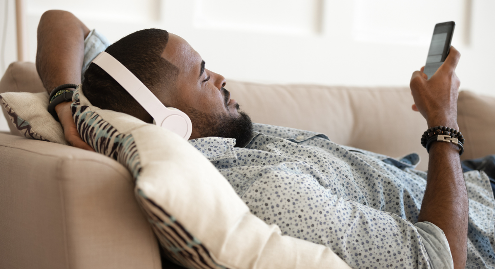 Man relaxing on the couch, listening to Feed.fm relaxing music