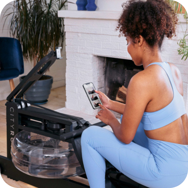 woman looking at digital fitness app on cityrow connected rowing machine