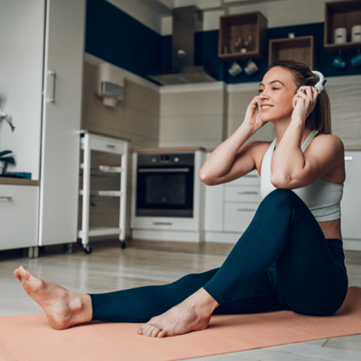 woman on yoga mat with headphones in kitchen