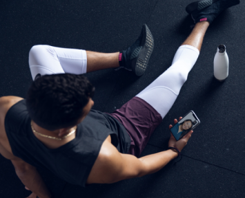Man seating in stretching position using Future digital fitness app