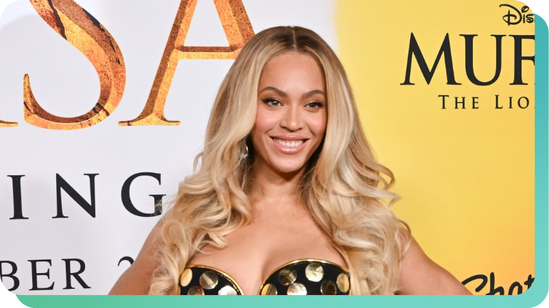 Beyoncé smiling at a premiere event, wearing a black and gold top, with long blonde hair