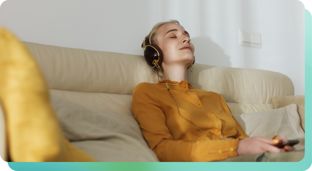 Woman on couch with her eyes closed listening to music