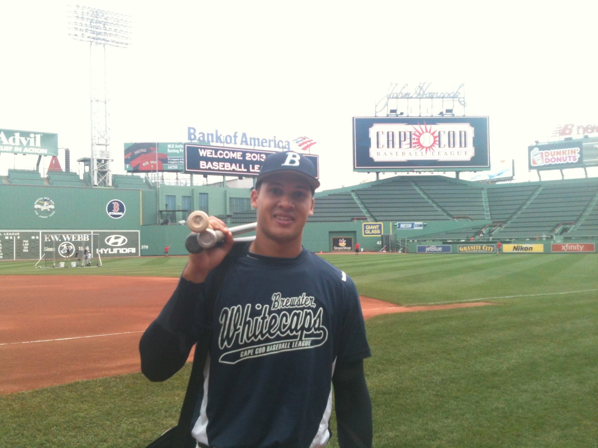 Nick standing on the field wearing a Brewster Whitecaps jersey and holding two baseball bats over his shoulder