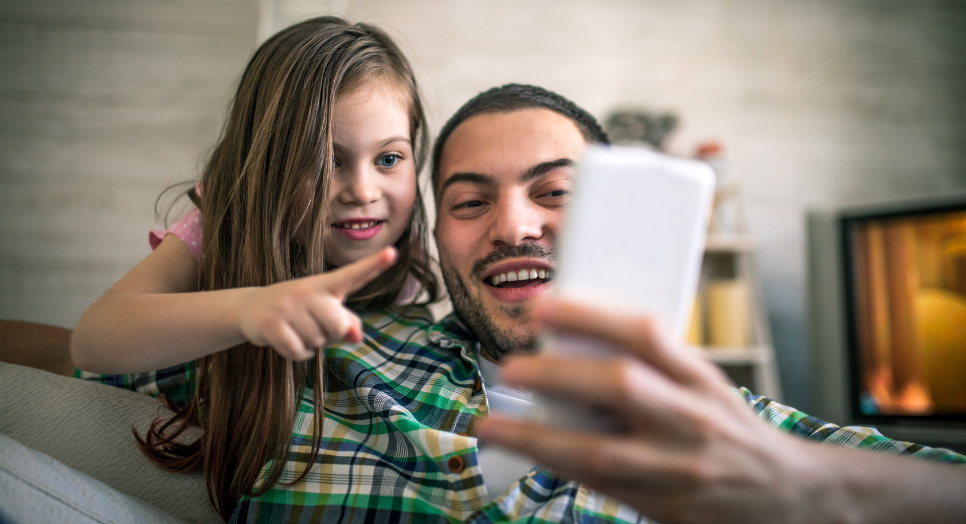 Father and daughter looking at family-friendly content on phone
