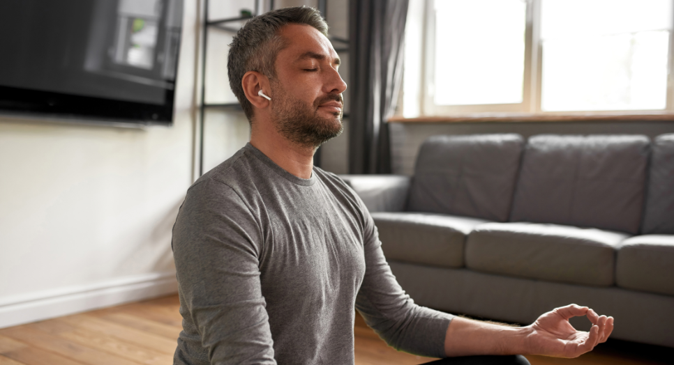 Man at home using meditation app listening to meditation music to relax
