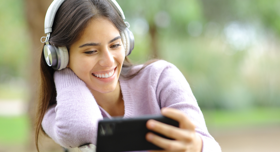 Woman outside wearing headphones while listening to music from an eCard