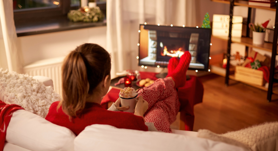 Woman watching yule log on TV with relaxing holiday music