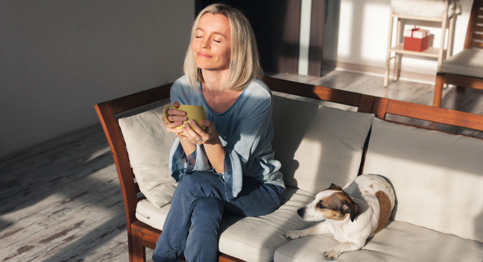 Woman with face in the sun on couch with dog