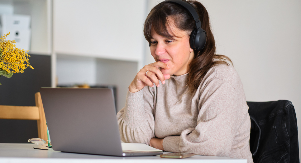 Woman working on laptop with headphones researching music licensing for ecards