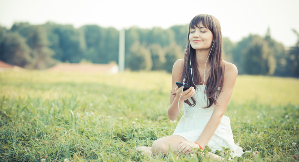 Woman in the fields listening to Feed.fm music