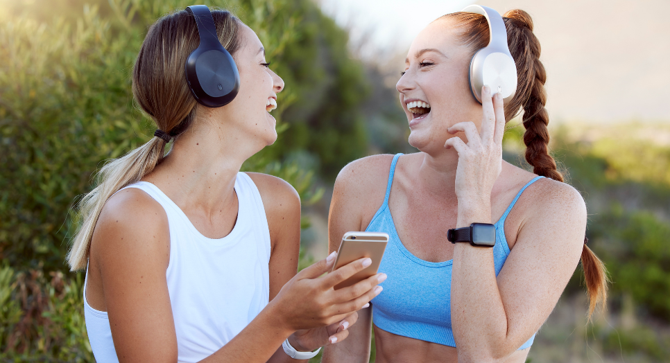 two women listening to licensed workout music on headphones outside