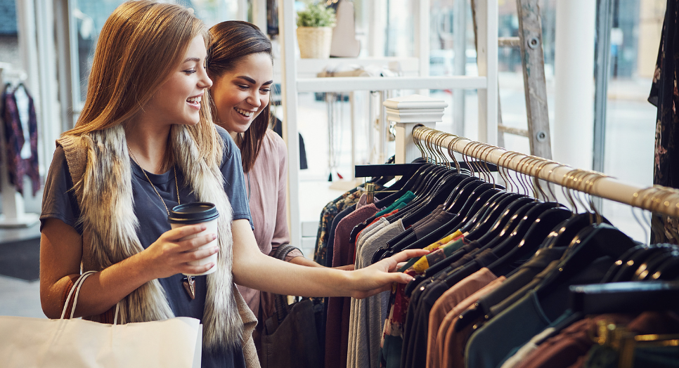 two girls outside shopping in a store for clothes while listening to feed originals in the background